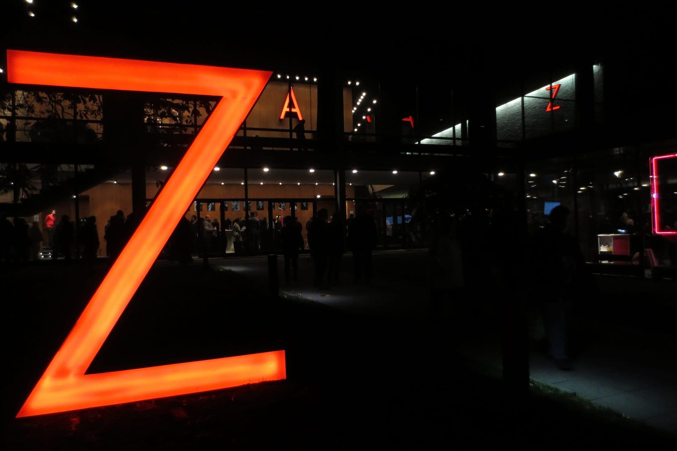 The forecourt of the Haus der Berliner Festspiele during the jazz festival, with banners on the low modernist façade and people standing outside the glass entrance.