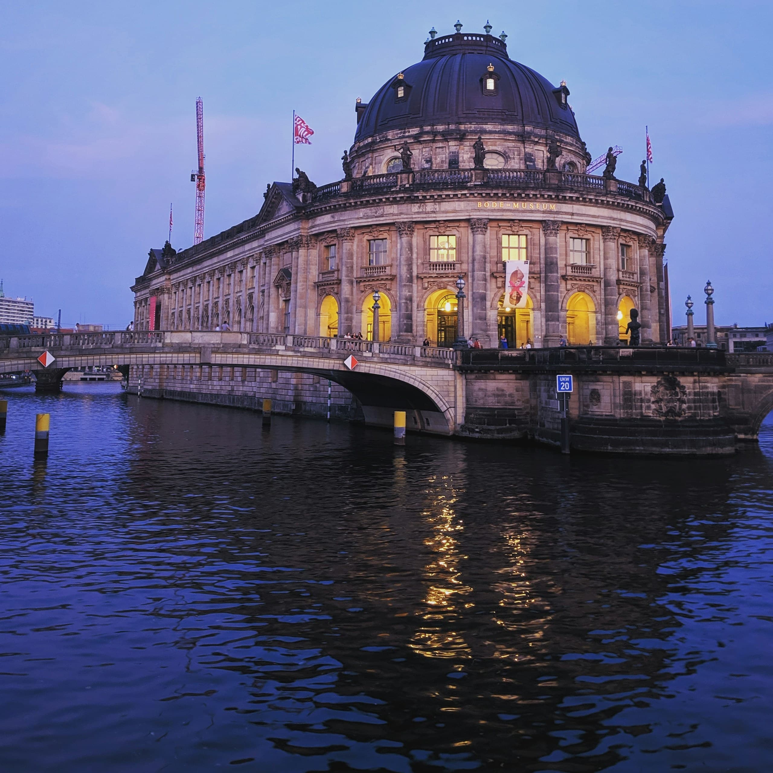 The Bode-Museum on Museum Island at dusk, its windows lit and reflected in the Spree.