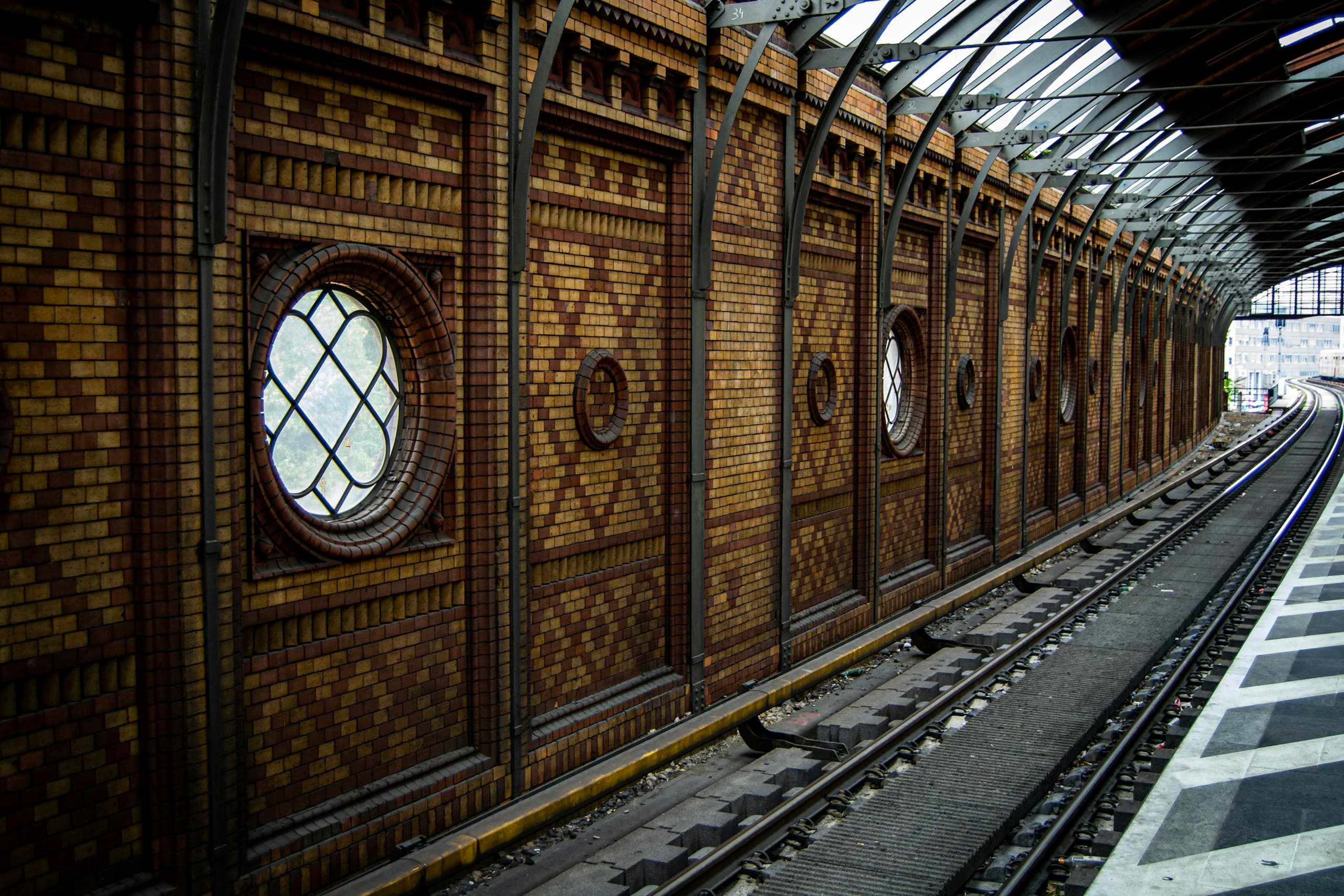 The tiled arches of Hackescher Markt S-Bahn station, its round windows lit along the curved platform wall.