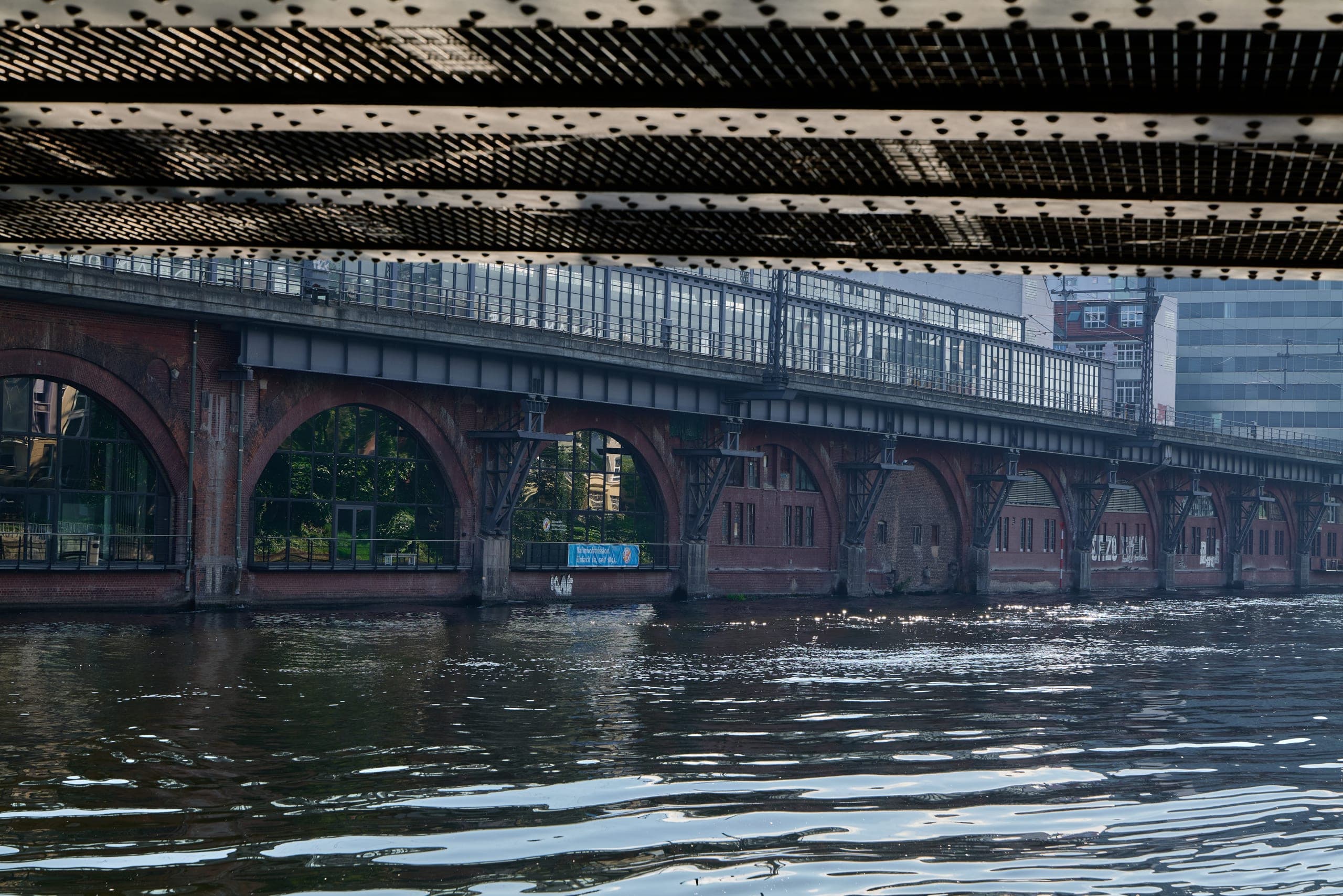 The Spree under Jannowitzbrücke: dark water, a red-brick S-Bahn viaduct, and the underside of the road bridge above.