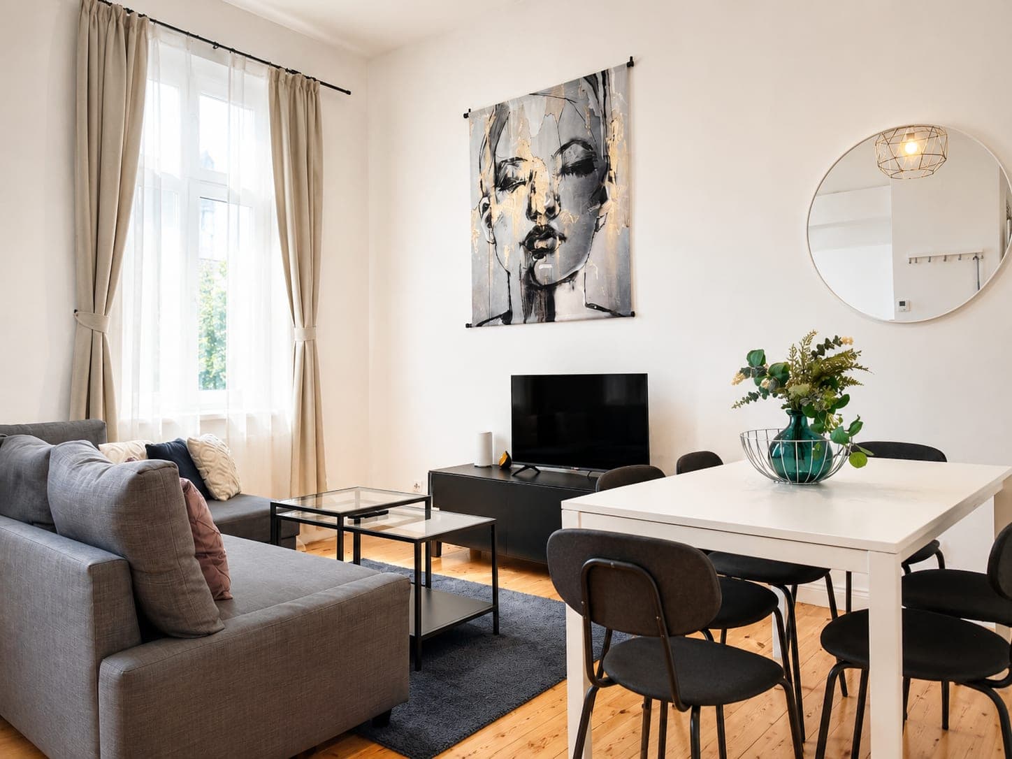 A living room with a dining table under a pendant lamp and pale walls.